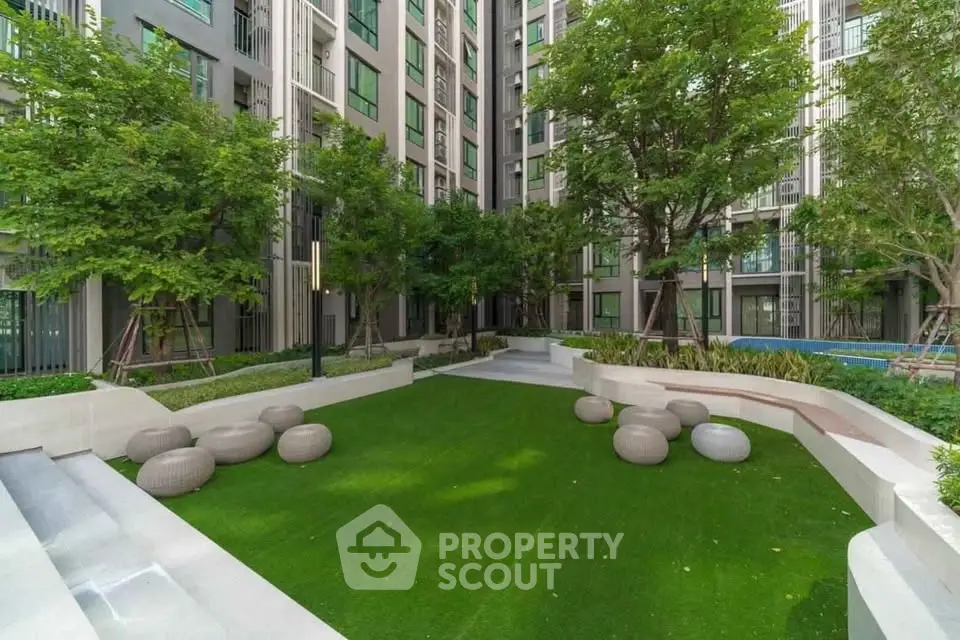 Modern apartment building with lush garden and seating area, perfect for relaxation.