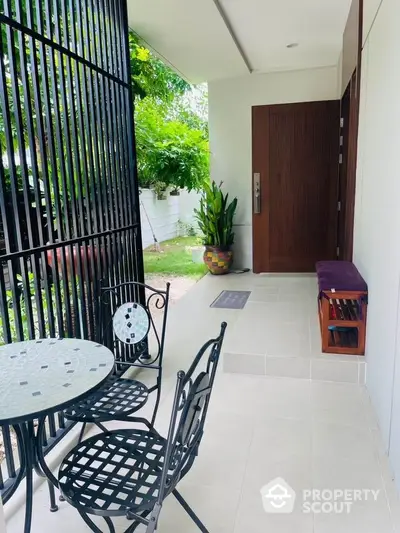 Charming modern entrance with stylish outdoor seating and lush greenery.