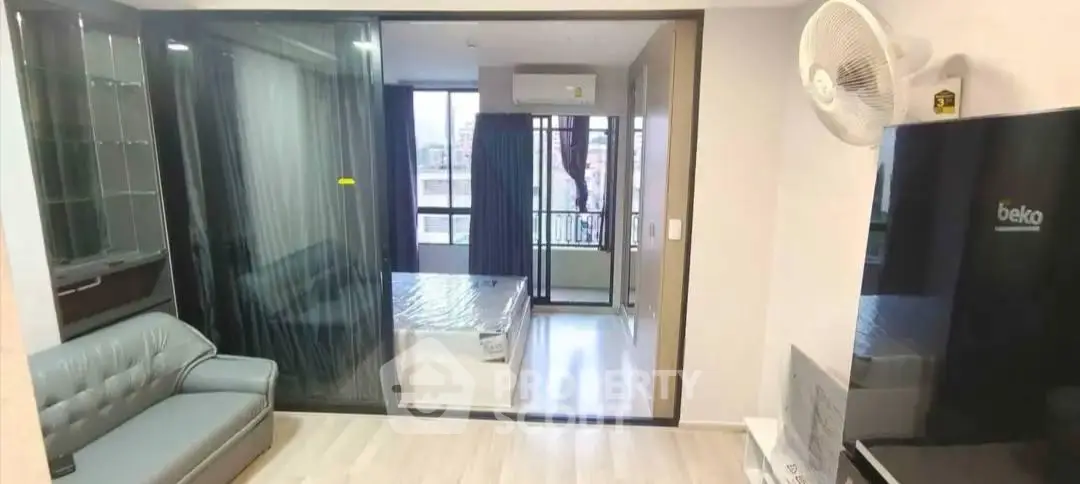 Modern apartment interior with spacious living room and bedroom, featuring sleek furniture and large windows.