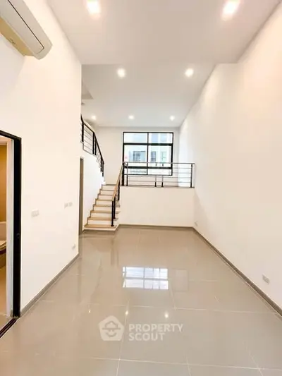 Spacious modern living room with high ceiling and sleek staircase in a contemporary home.