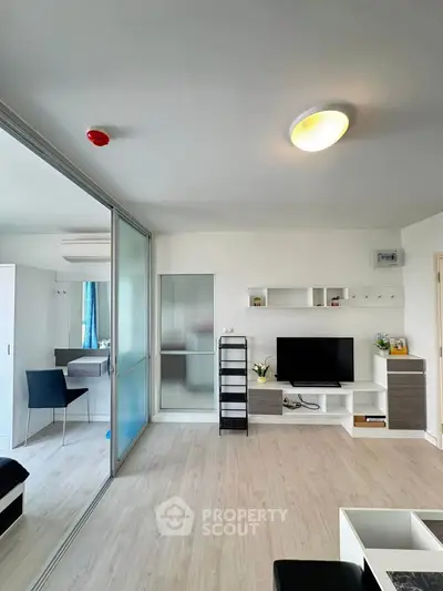 Modern living room with sleek design and natural light, featuring a TV unit and sliding glass doors.