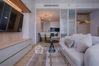 Modern living room with sleek furniture and open kitchen layout, featuring a cozy sofa and stylish decor.