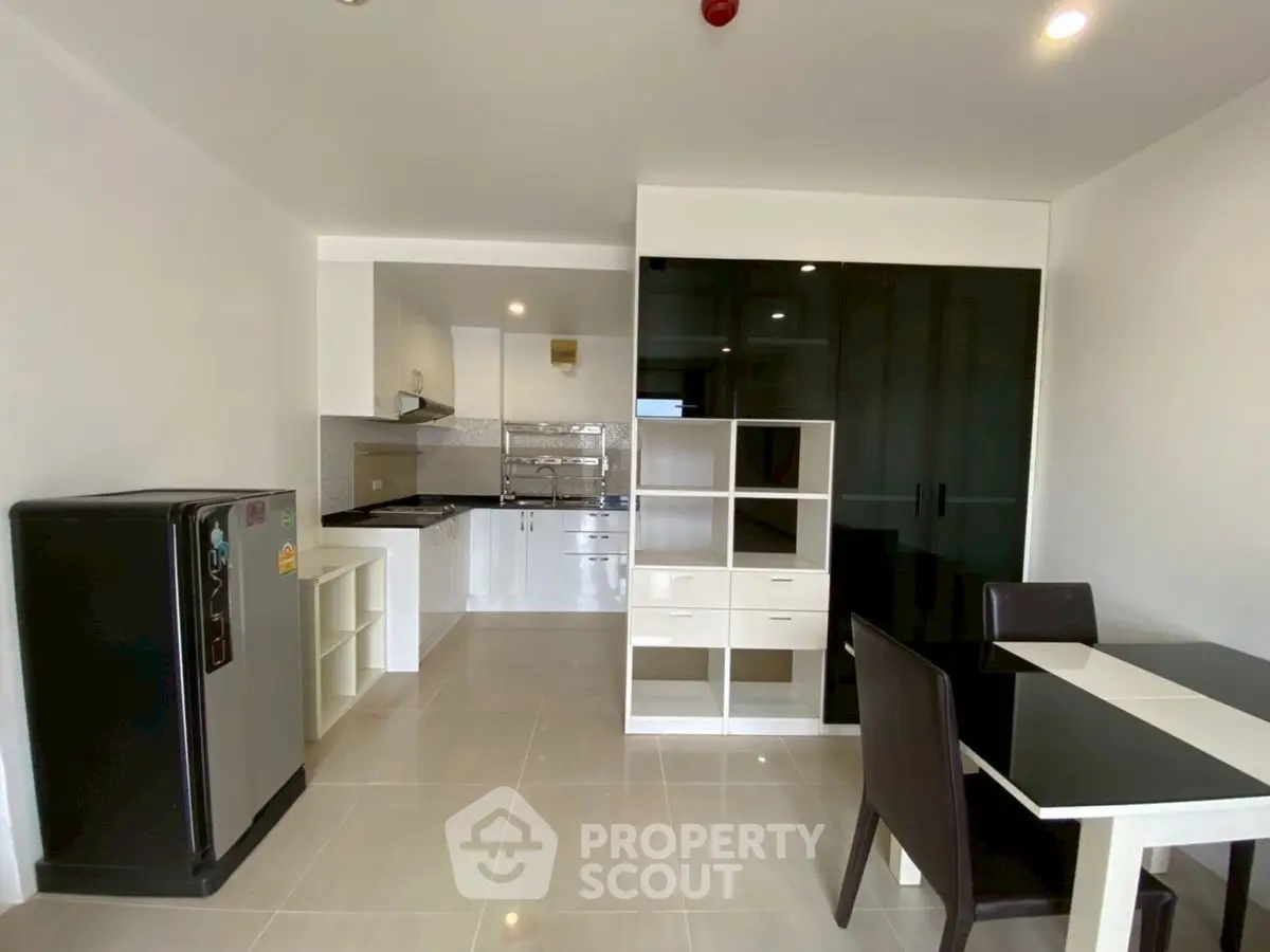 Modern kitchen and dining area with sleek black and white furniture, spacious layout.