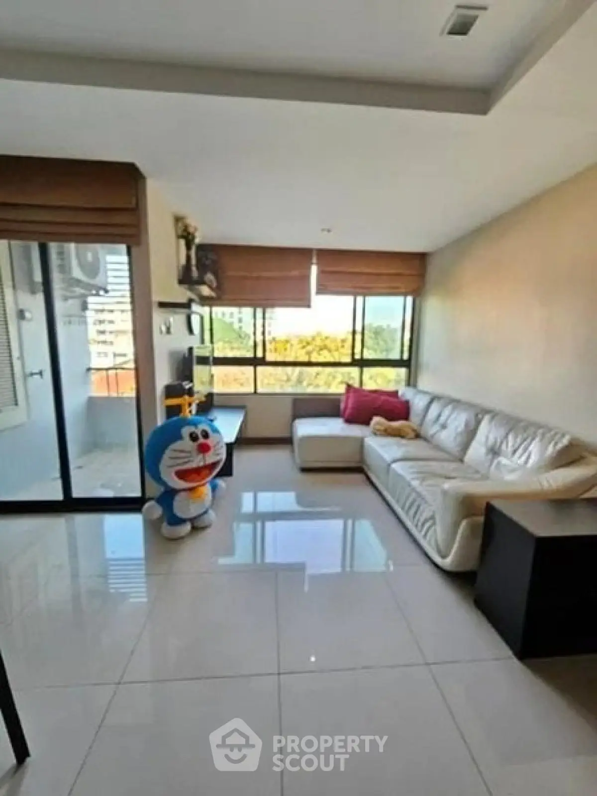 Spacious living room with large windows and modern decor, featuring a plush white sofa and glossy tiled floors.