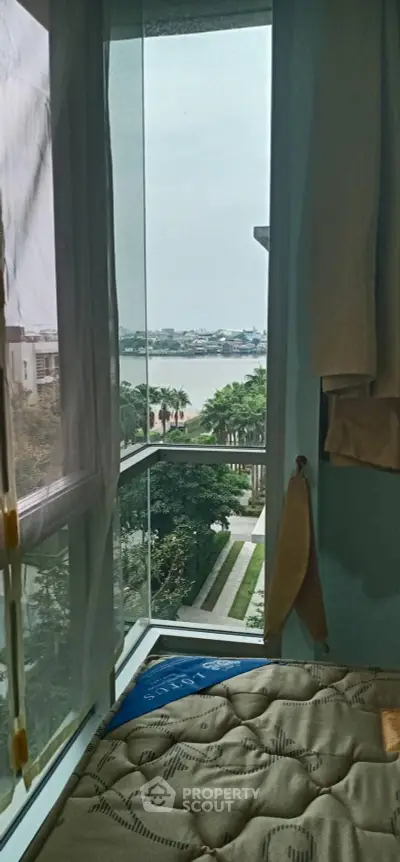 Cozy bedroom with a stunning view of the river and lush greenery from the window.