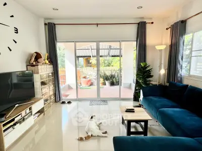 Spacious living room with modern decor and large windows opening to a garden view.