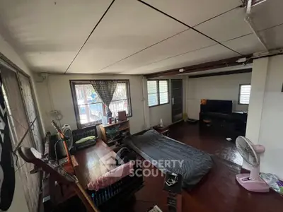 Cozy living room with wooden floors and natural light, featuring a desk, TV, and comfortable seating area.