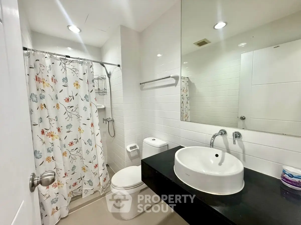 Modern bathroom with sleek fixtures and floral shower curtain