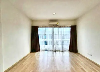 Spacious empty room with large window and wooden flooring, perfect for customization.