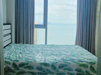 Cozy bedroom with stunning ocean view through large window, perfect for relaxation and tranquility.