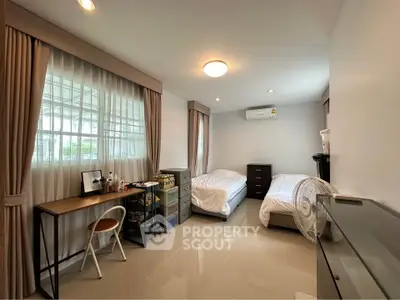 Spacious bedroom with twin beds, study desk, and modern decor.
