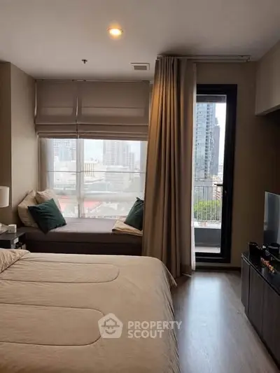 Cozy bedroom with city view and balcony access, featuring elegant decor and natural light.