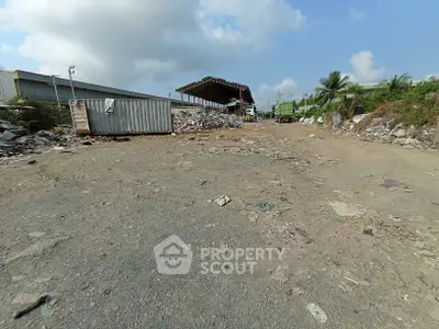 Spacious industrial yard with storage containers and open warehouse, ideal for logistics and manufacturing.