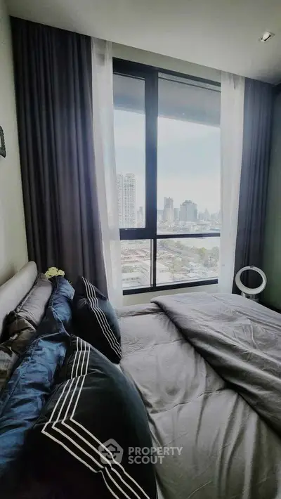 Modern bedroom with city view, featuring stylish bedding and large window for natural light.