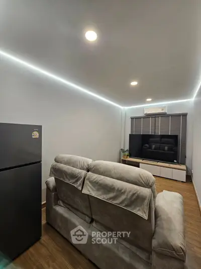 Modern living room with cozy sofa, sleek TV setup, and ambient lighting for a comfortable lifestyle.