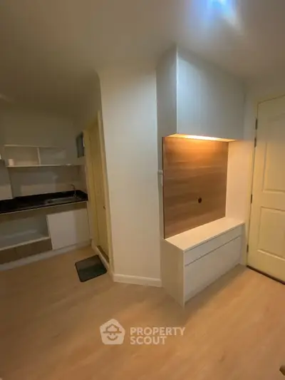 Modern compact kitchen with sleek cabinetry and wood accents in a cozy apartment.