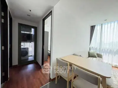 Modern apartment interior with dining area and balcony view, featuring sleek furniture and natural light.