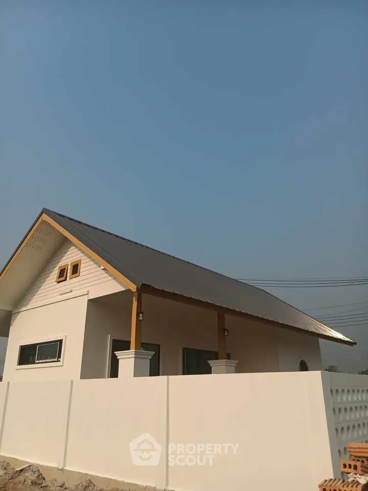 Charming single-story house with modern design and white fence under clear blue sky.