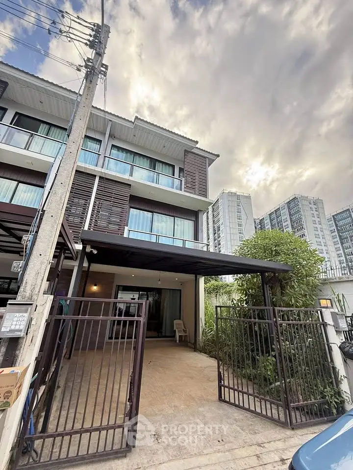 Modern townhouse exterior with gated entrance and urban surroundings.