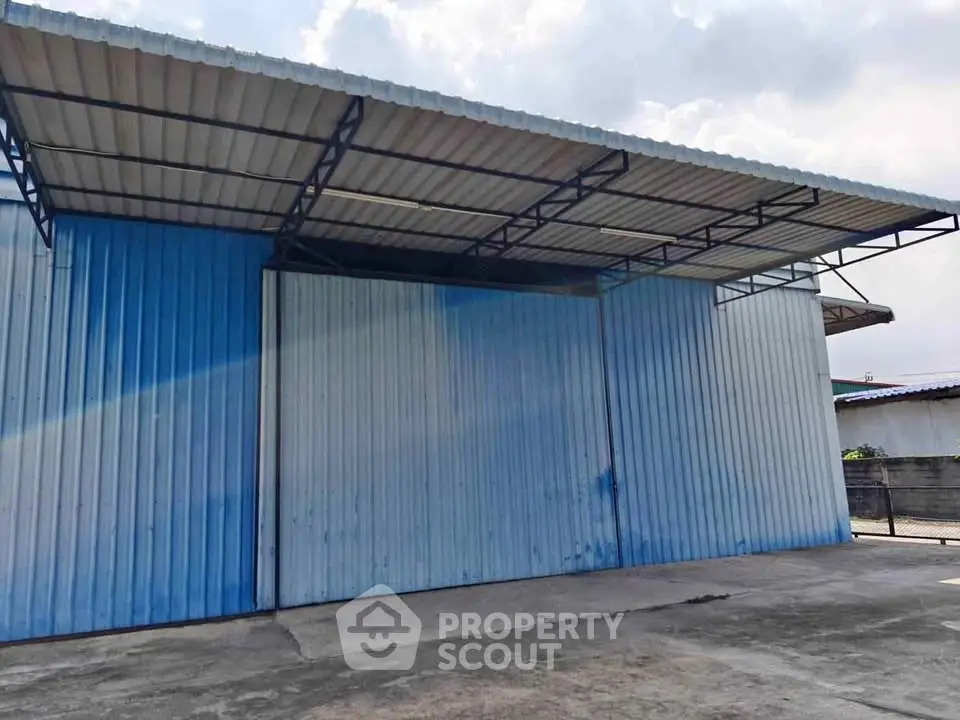 Spacious industrial warehouse with metal siding and large covered area, ideal for storage or business operations.
