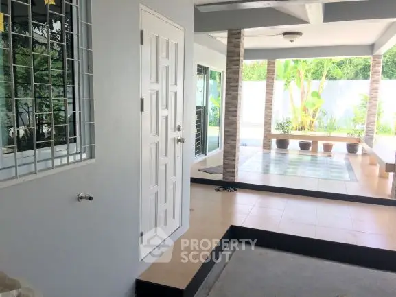 Spacious covered patio with tiled flooring and garden view, perfect for outdoor relaxation.