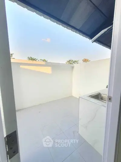 Spacious outdoor area with sink and tiled flooring, perfect for utility or relaxation.