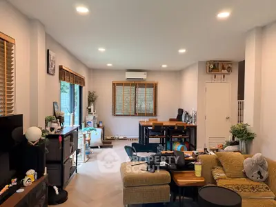 Spacious living room with modern decor and natural light, featuring a cozy seating area and dining space.