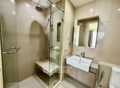 Modern bathroom with glass shower and sleek vanity in contemporary apartment.