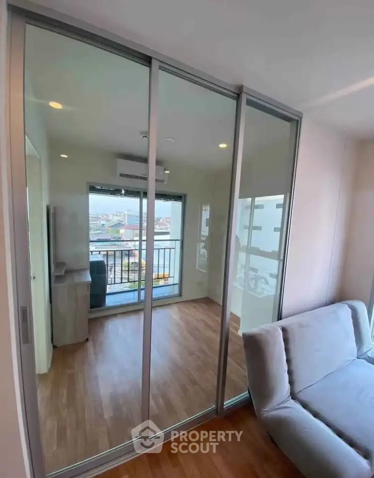 Modern living room with glass sliding doors and balcony view in urban apartment.