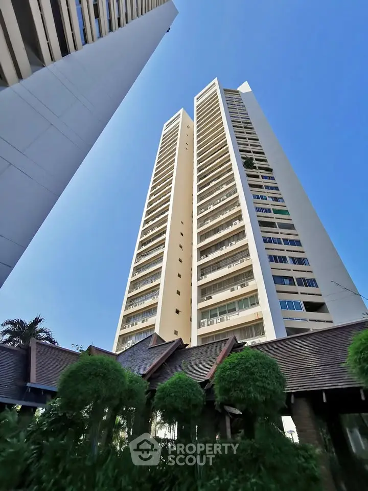 Stunning high-rise building with lush greenery and clear blue sky