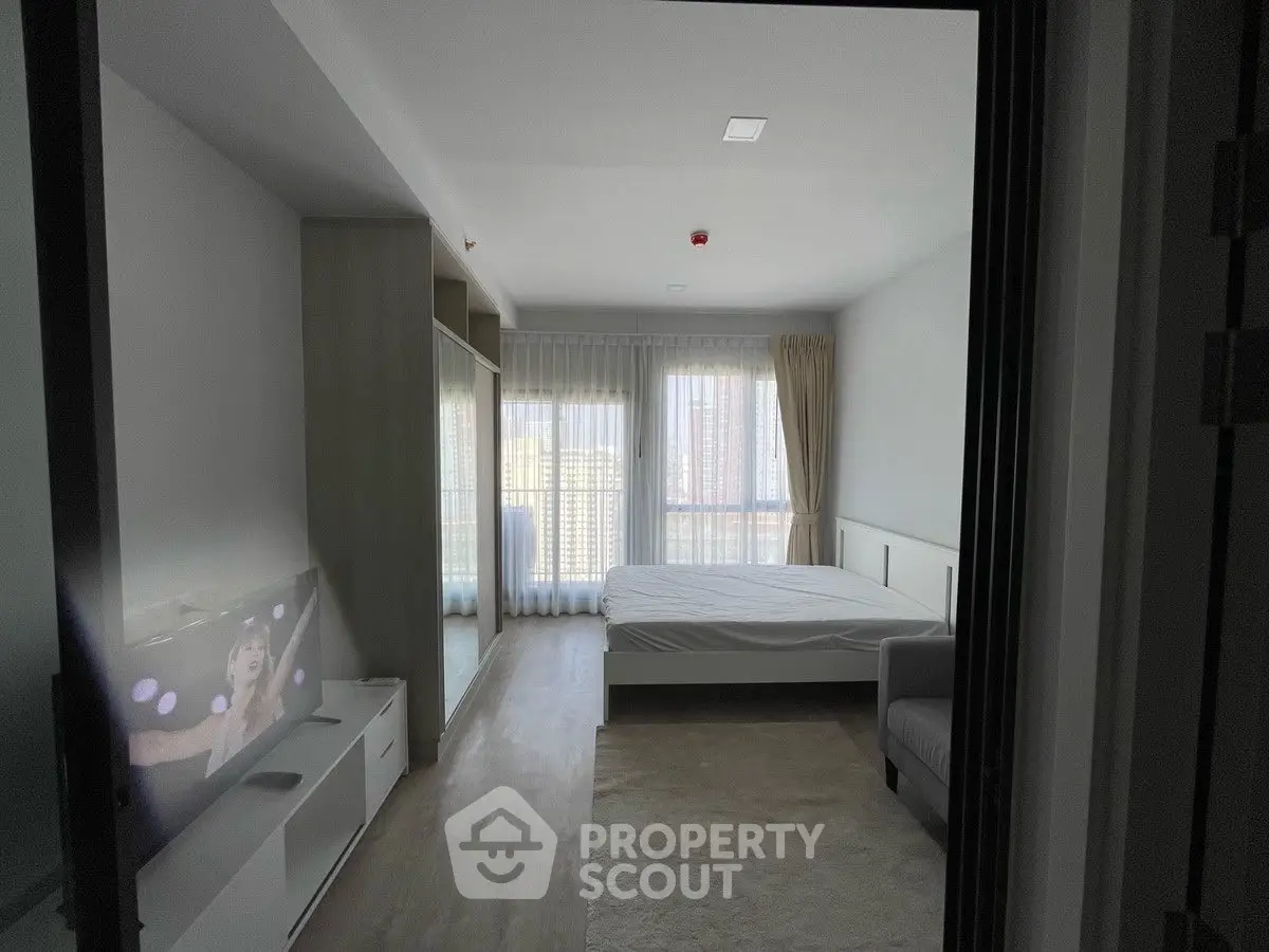 Modern bedroom with large window and built-in wardrobe, featuring a cozy bed and sleek TV setup.