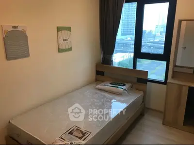 Cozy bedroom with city view, featuring a single bed and modern furnishings, ideal for urban living.