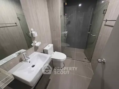Modern bathroom with sleek design, featuring a glass shower enclosure and contemporary fixtures.
