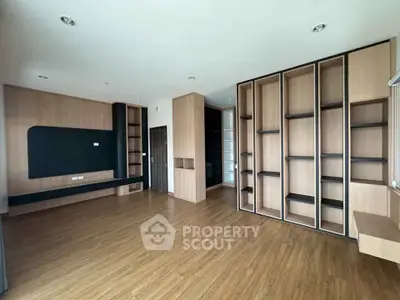 Spacious modern living room with built-in wooden shelves and sleek flooring