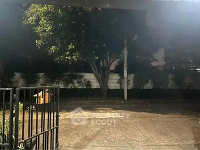 Spacious outdoor area with trees and gated entrance, perfect for evening relaxation.