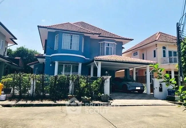 Charming two-story blue house with carport in a serene suburban neighborhood.