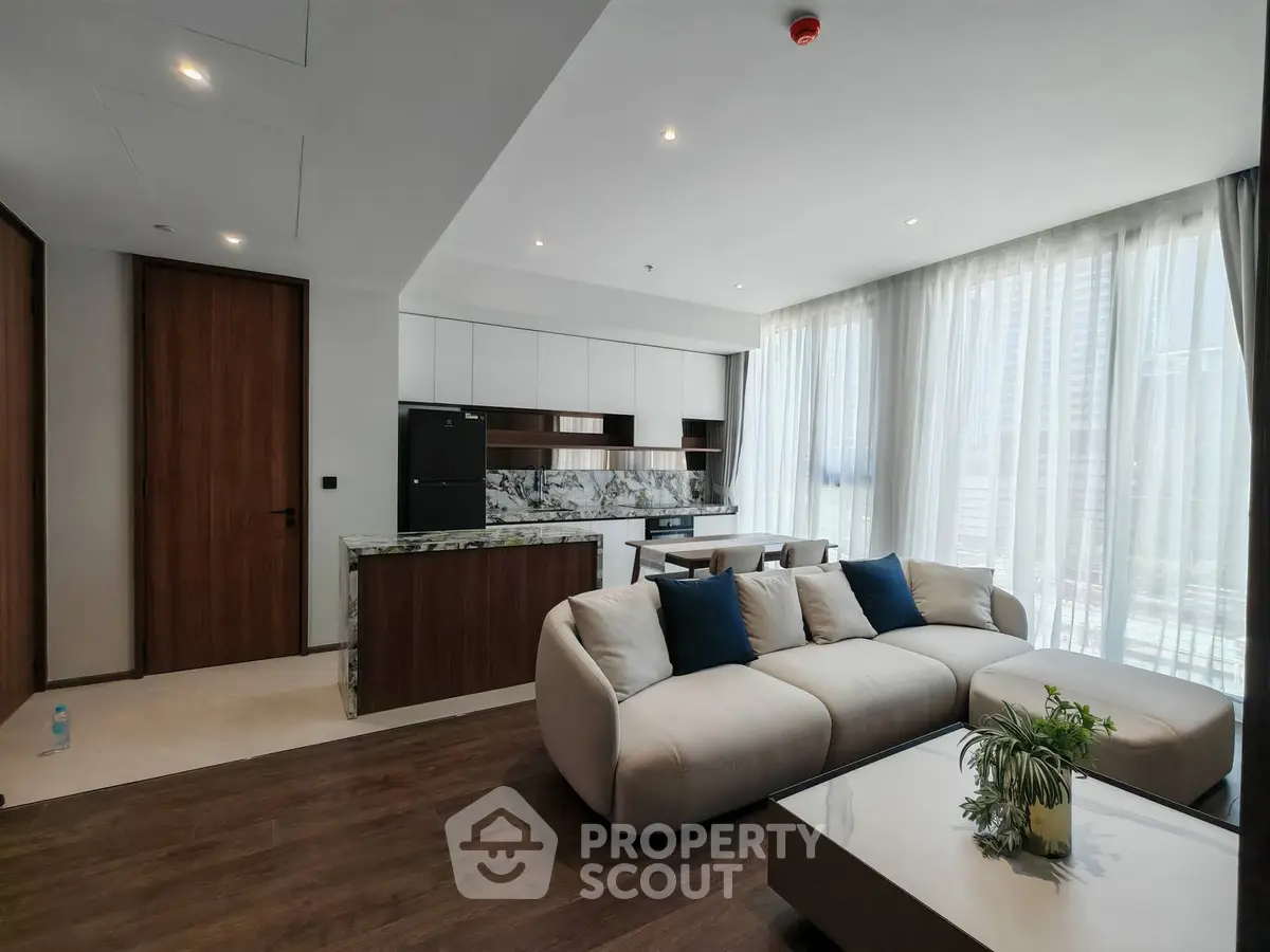 Modern open-layout living room with stylish kitchen and large windows in a luxury apartment.