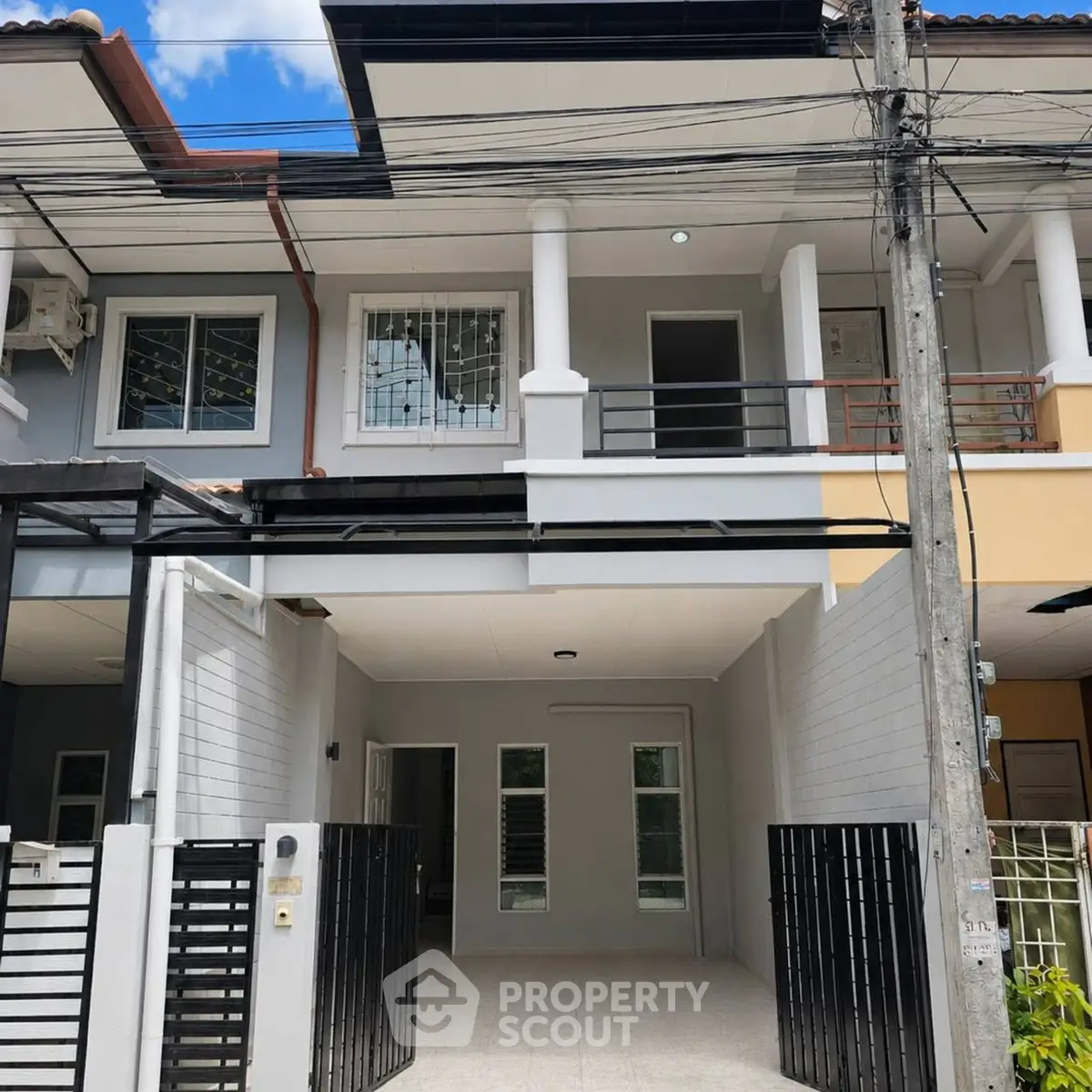 Modern townhouse exterior with gated entrance and balcony, ideal for urban living.