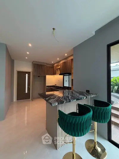 Modern kitchen with elegant marble countertop and stylish green bar stools in a sleek open layout.