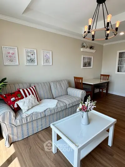 Charming living room with cozy striped sofa, elegant chandelier, and stylish decor in a modern apartment.