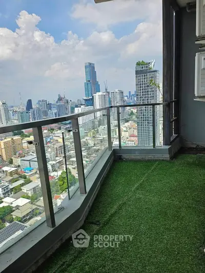 Stunning cityscape view from a high-rise balcony with artificial grass flooring.