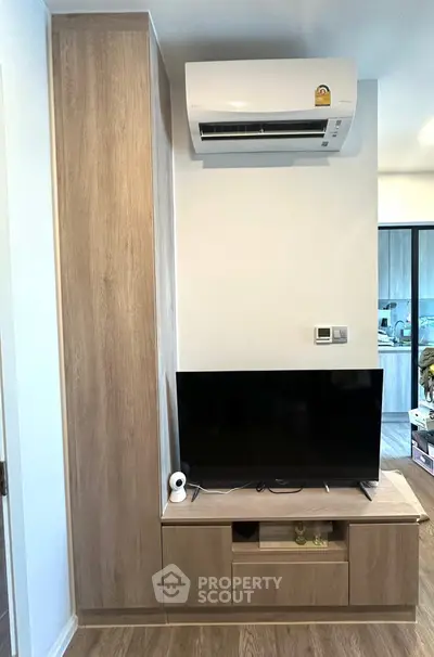 Modern living room with air conditioner and TV setup, featuring sleek wooden cabinetry.
