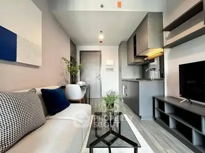 Modern living room with sleek kitchen in open layout, stylish decor, and cozy ambiance.