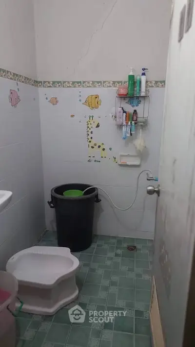Compact bathroom with green tiled floor and wall-mounted storage shelves.
