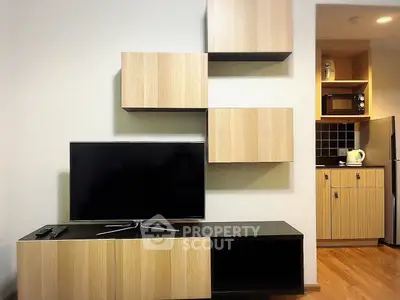 Modern living room with stylish wooden TV cabinet and sleek kitchen appliances.