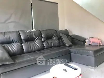 Modern living room with sleek black leather sectional sofa and minimalist decor.