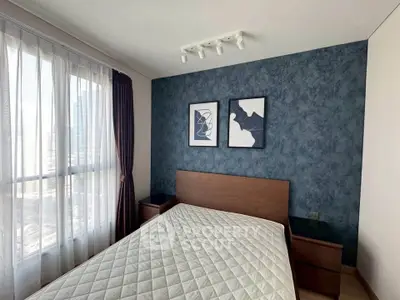 Modern bedroom with stylish decor and large window offering city views.
