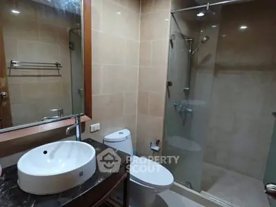 Modern bathroom with glass shower and elegant sink in real estate property.