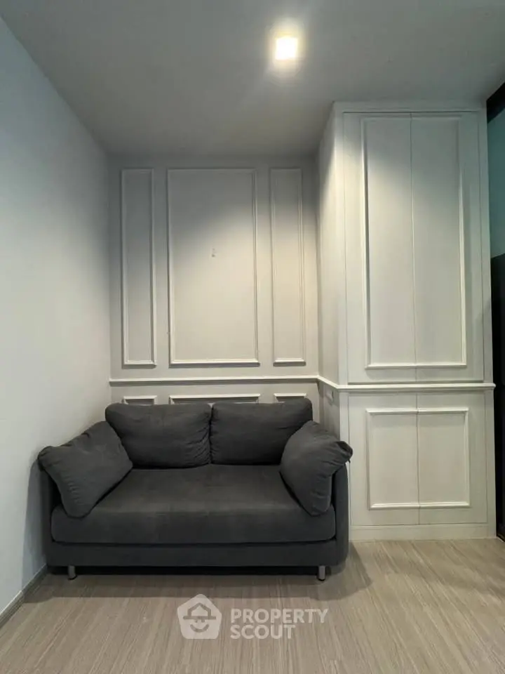 Cozy living room with modern gray sofa and elegant white paneling, perfect for relaxation.