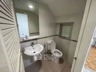 Compact bathroom with modern fixtures and tiled walls, featuring a sleek sink and toilet.